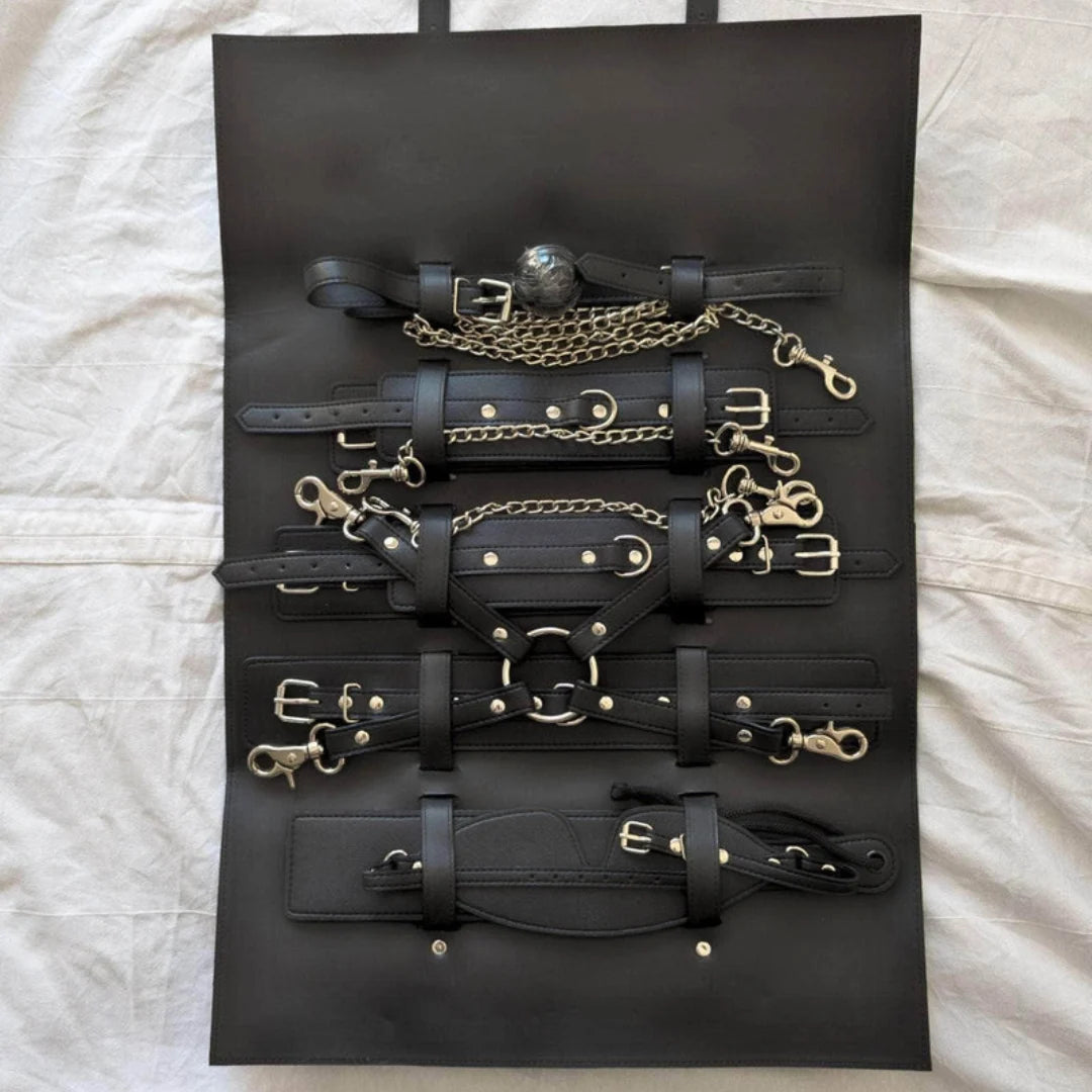 Collection of black leather straps and gold hardware on a black display board.