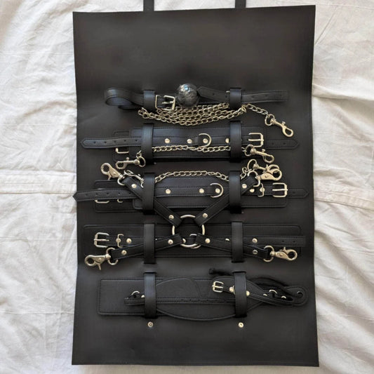 Collection of black leather straps and gold hardware on a black display board.