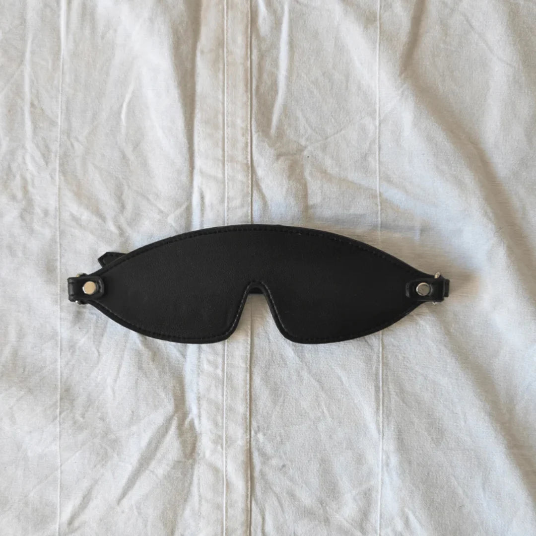 Black Blind fold mask on a white fabric background