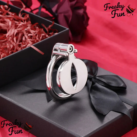 Silver sissy chastity cage with ring with a black bow on a red and black background with 'Freaky Fun' branding.