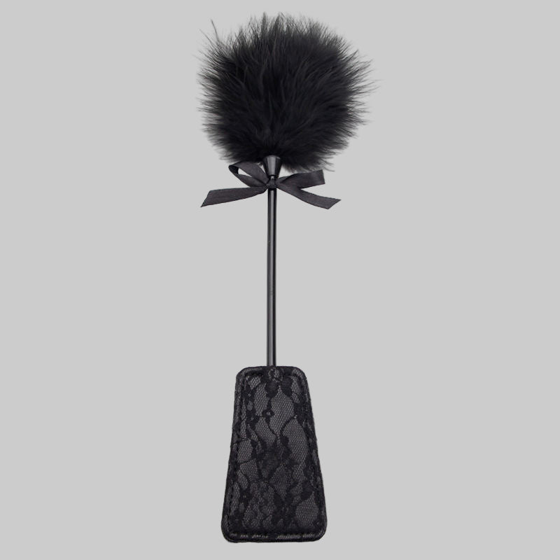 Black lace paddle with a fluffy black top on a white background